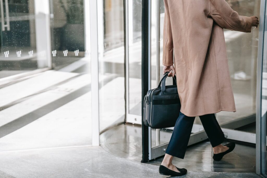 anonymous fashionable businesswoman walking through revolving door